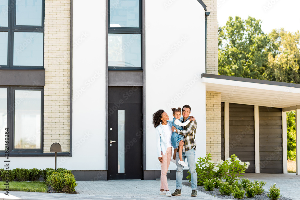 Φωτογραφία full length view of african american family standing near new house while father