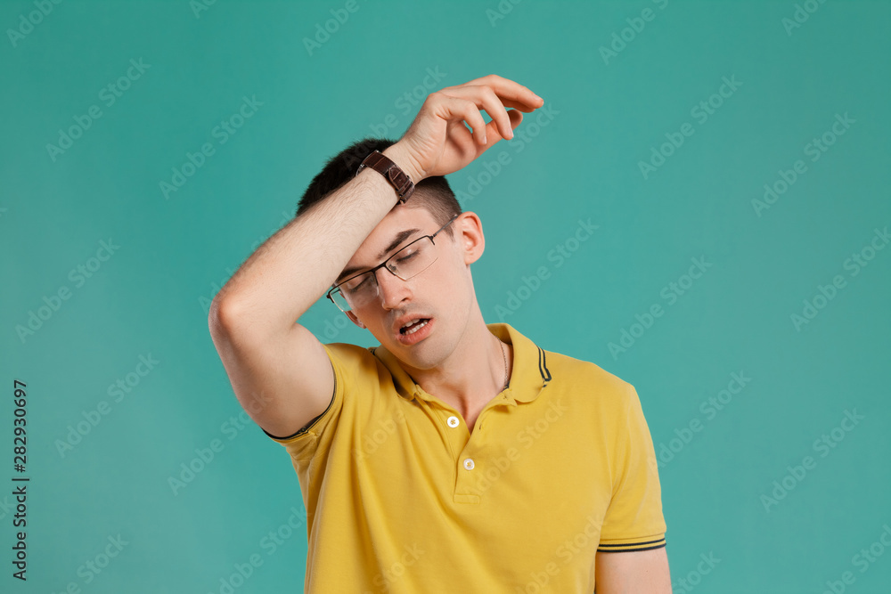 Handsome guy in a yellow casual t-shirt is posing over a blue background. Handsome guy in a yellow casual t-shirt is posing over a blue background.