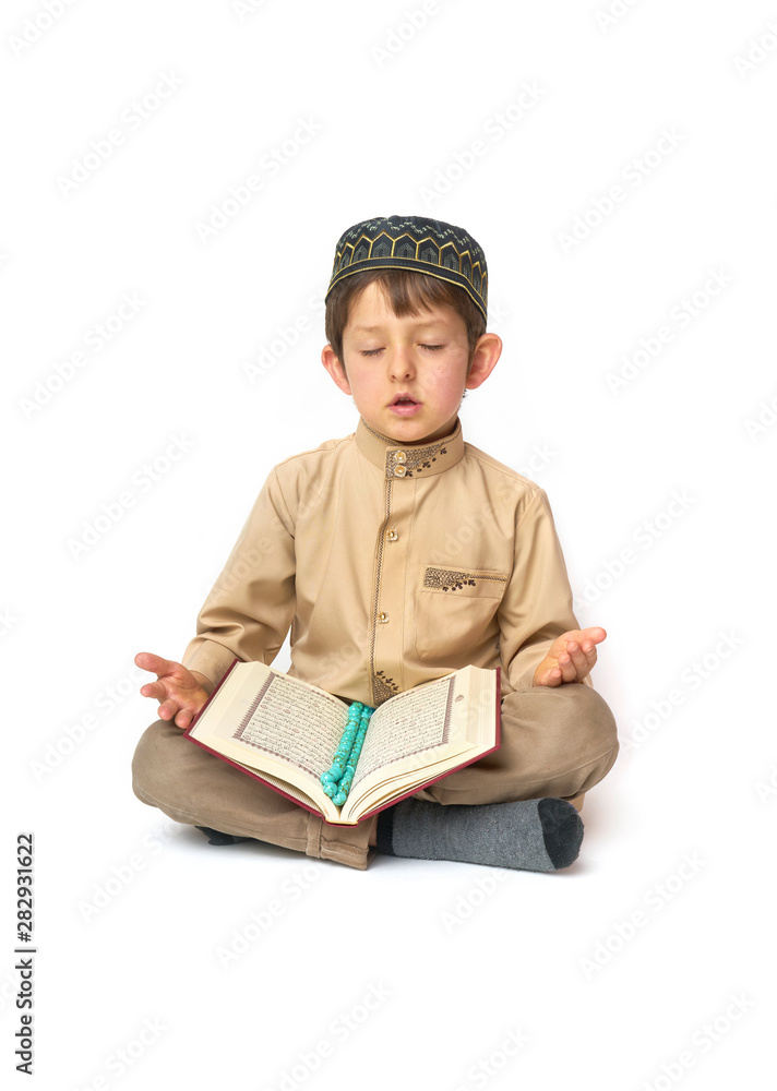 Little boy praying and holding Koran with rosary beads on white background Little boy praying and holding Koran with rosary beads on white background