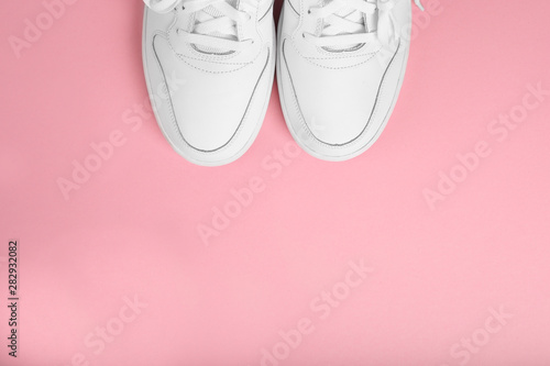Stylish summer white running shoes on a pink background, top view. Flat lay with copy space for text