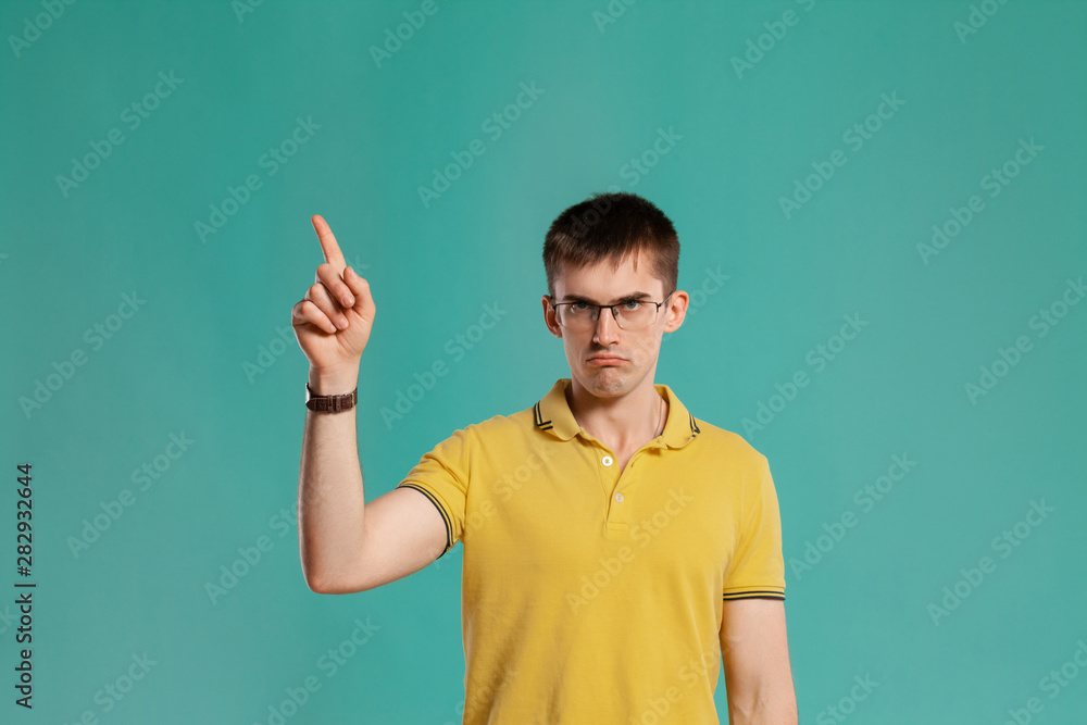 Handsome guy in a yellow casual t-shirt is posing over a blue background. Handsome guy in a yellow casual t-shirt is posing over a blue background.