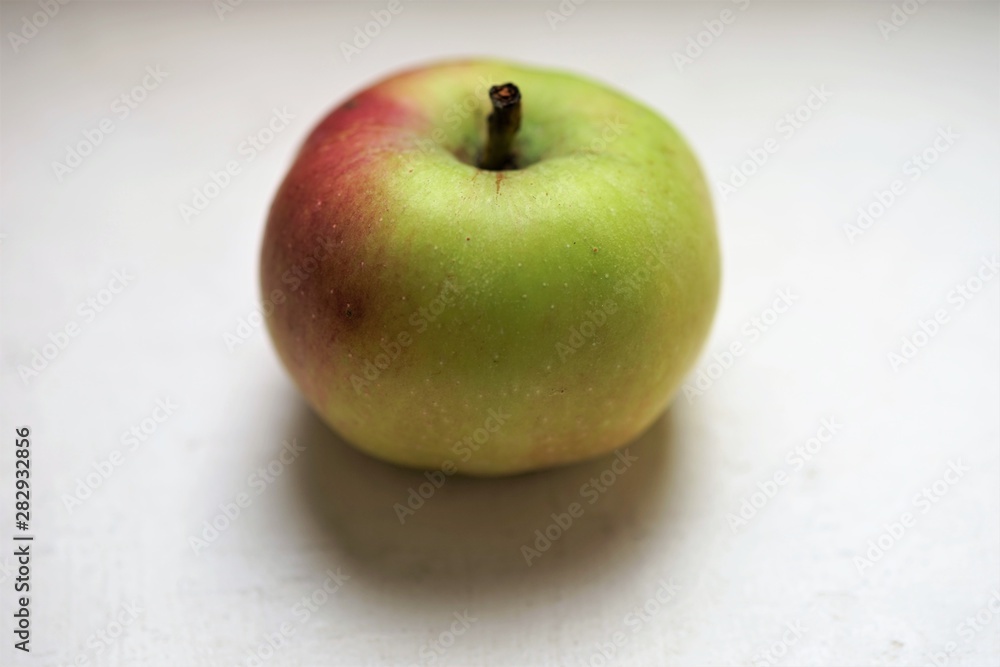 small green red apple on the white table small green red apple on the white table
