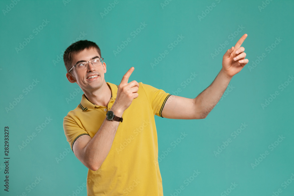 Handsome guy in a yellow casual t-shirt is posing over a blue background. Handsome guy in a yellow casual t-shirt is posing over a blue background.