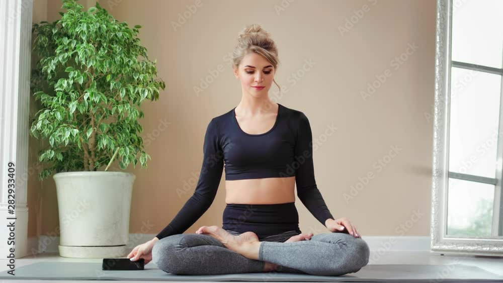 Attractive flexible young woman practicing yoga at home using smartphone full shot Attractive flexible young woman practicing yoga at home using smartphone full shot