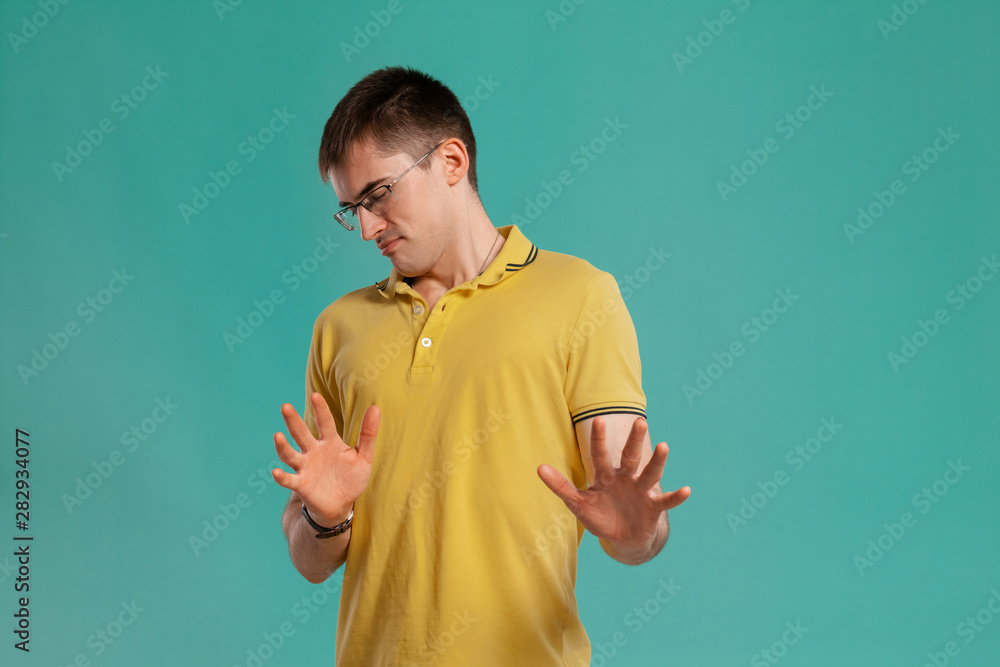 Handsome guy in a yellow casual t-shirt is posing over a blue background. Handsome guy in a yellow casual t-shirt is posing over a blue background.