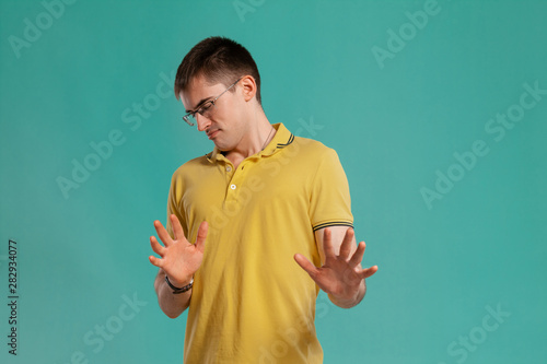 Handsome guy in a yellow casual t-shirt is posing over a blue background.