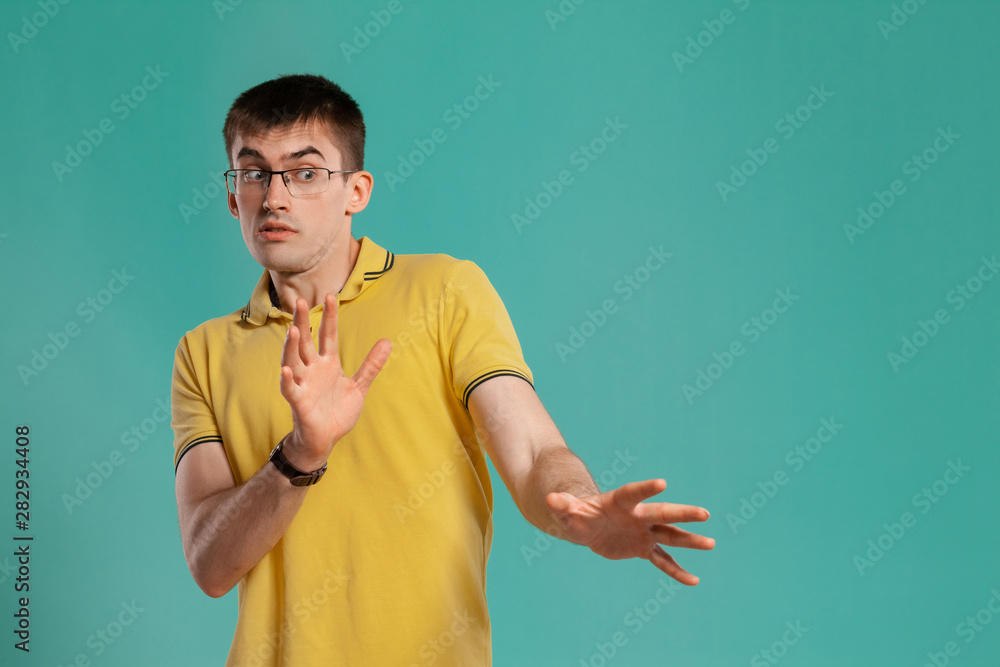 Handsome guy in a yellow casual t-shirt is posing over a blue background. Handsome guy in a yellow casual t-shirt is posing over a blue background.