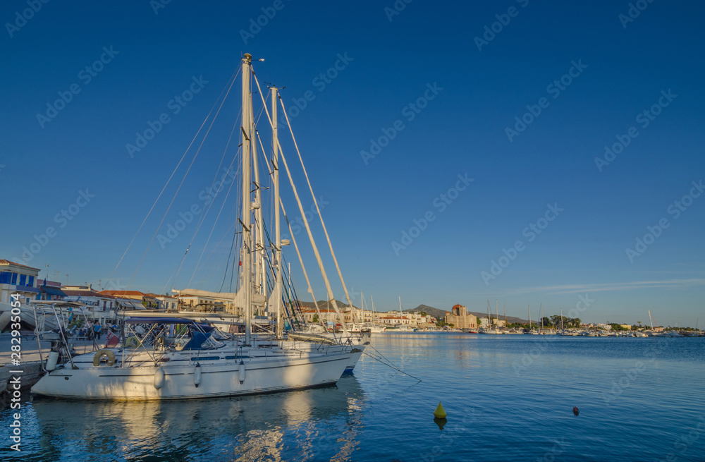 Port of Aegina town with yachts and fishermen boats docked in Aegina island, Saronic gulf, Greece, at sunrise. Port of Aegina town with yachts and fishermen boats docked in Aegina island, Saronic gulf, Greece, at sunrise.