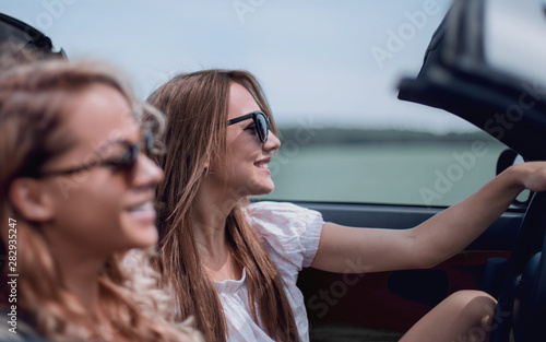 two fashionable girls travel in a convertible car. © ASDF