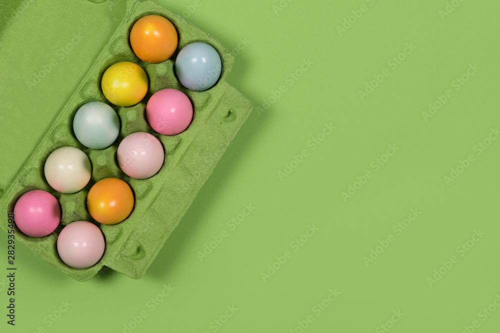 Easter background with a green carton egg box with pastel colored easter eggs in it on a green background with space for copy Easter background with a green carton egg box with pastel colored easter eggs in it on a green background with space for copy