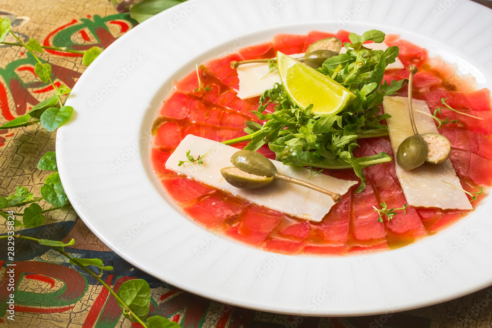 Marbled beef carpaccio with arugula, lemon and parmesan cheese. Top view, flat lay with copy space Side view Marbled beef carpaccio with arugula, lemon and parmesan cheese. Top view, flat lay with copy space Side view