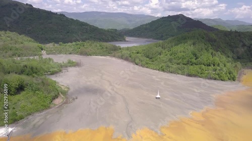 Forward motion aerial showing the striking colours of devastation pollution and environmental disaster Geamana at Rosia Montana a Romainian mining town. photo