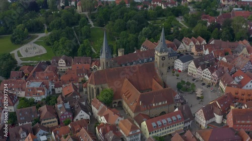 Aerial view from the old part of the city Öhringen in Germany.  Camera zooms in and tilts down over the collegiate church and marketplace, and then over city gardens. photo