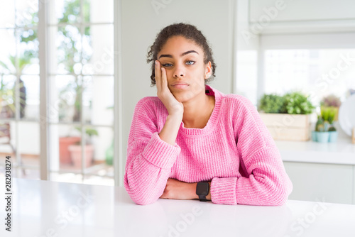 Beautiful african american woman with afro hair wearing casual pink sweater thinking looking tired and bored with depression problems with crossed arms.