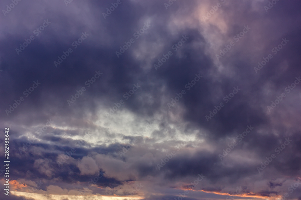 Dark rain clouds during sunset. Dramatic sky during sunset. Dark storm clouds with black and white highlights.