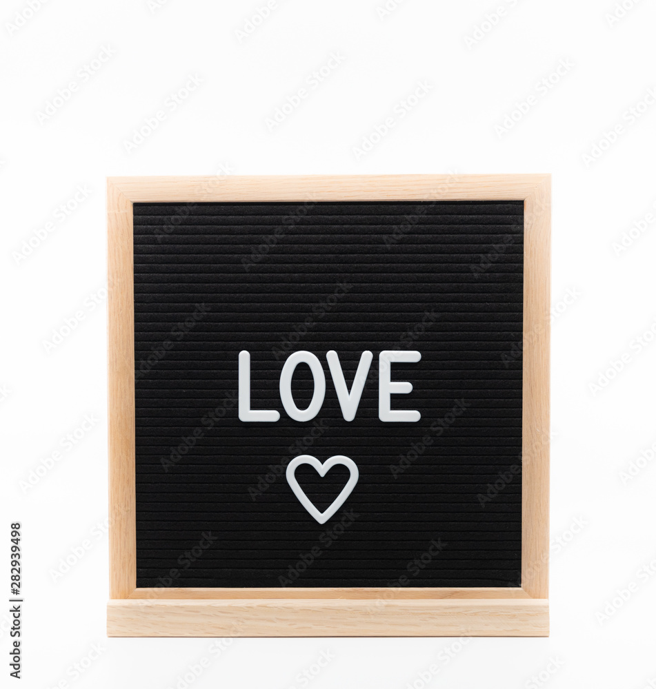 Text in english spelling 'Love' with a heart on black felt board in a wooden frame. Text in english spelling 'Love' with a heart on black felt board in a wooden frame.