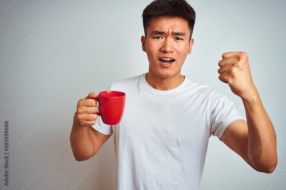 Asian chinese man holding red cup of coffee standing over isolated white background annoyed and frustrated shouting with anger, crazy and yelling with raised hand, anger concept Asian chinese man holding red cup of coffee standing over isolated white background annoyed and frustrated shouting with anger, crazy and yelling with raised hand, anger concept