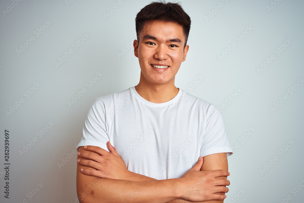 Obraz premium Young asian chinese man wearing t-shirt standing over isolated white background happy face smiling with crossed arms looking at the camera. Positive person.