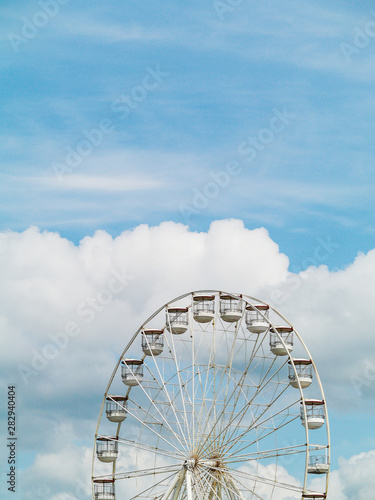 Fun wheel , ferris against cloudy sky. Fun fare and summer entertainment concept. Vertical image.