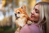 Young woman with dog in her arms on the background of beautiful nature. Autumn story. A love for animals.