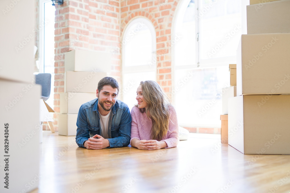 Young beautiful couple in love relaxing lying on the floor together with cardboard boxes around for moving to a new house Young beautiful couple in love relaxing lying on the floor together with cardboard boxes around for moving to a new house