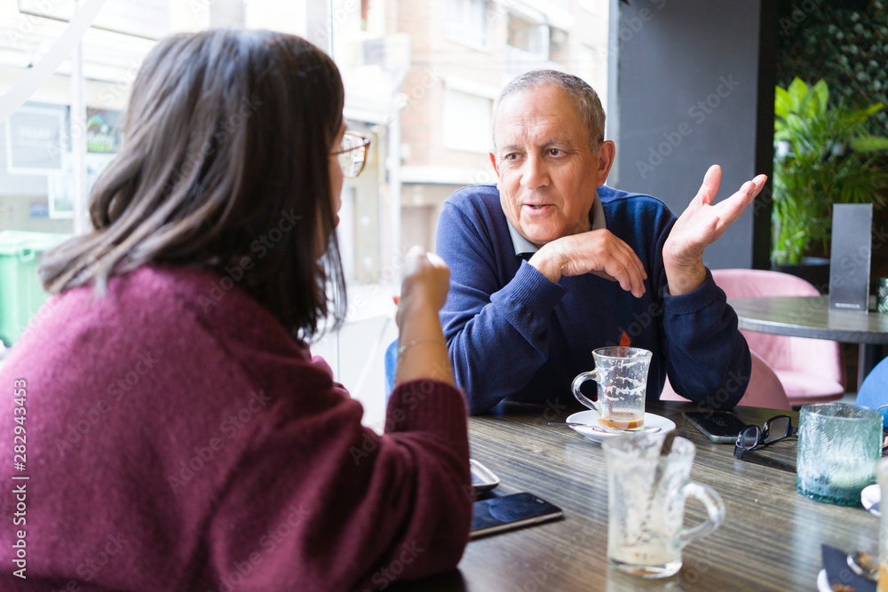 Senior man having a conversation with woman drinking coffee and relaxing, chatting at restaurant Senior man having a conversation with woman drinking coffee and relaxing, chatting at restaurant