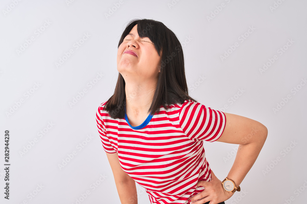 Young beautiful chinese woman wearing red striped t-shirt over isolated white background Suffering of backache, touching back with hand, muscular pain Young beautiful chinese woman wearing red striped t-shirt over isolated white background Suffering of backache, touching back with hand, muscular pain