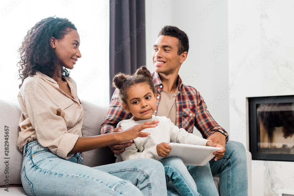 kid holding digital tablet while african american parents looking at each other kid holding digital tablet while african american parents looking at each other