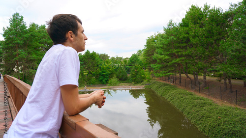 Smart man contemplate in the bridge over lake in the middle of park