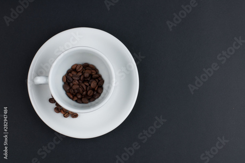 White cup of coffee and coffee beans isolated on black background