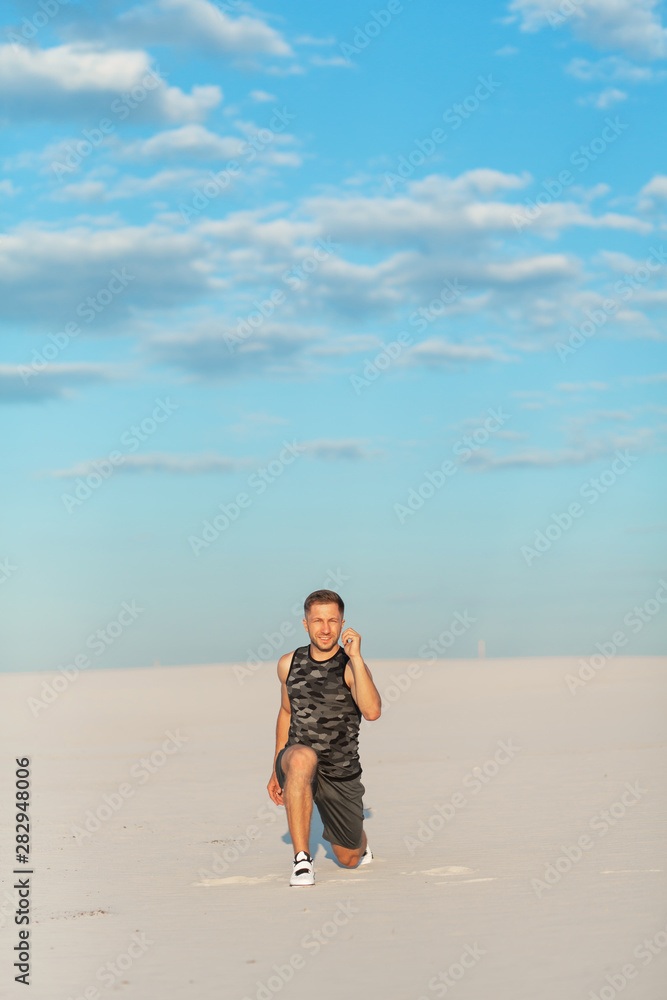 Fitness man doing exercises in sand desert. Sport concept