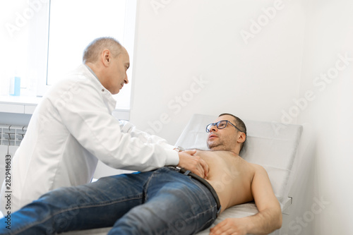Doctor physiotherapist examining his patients stomach in medical office