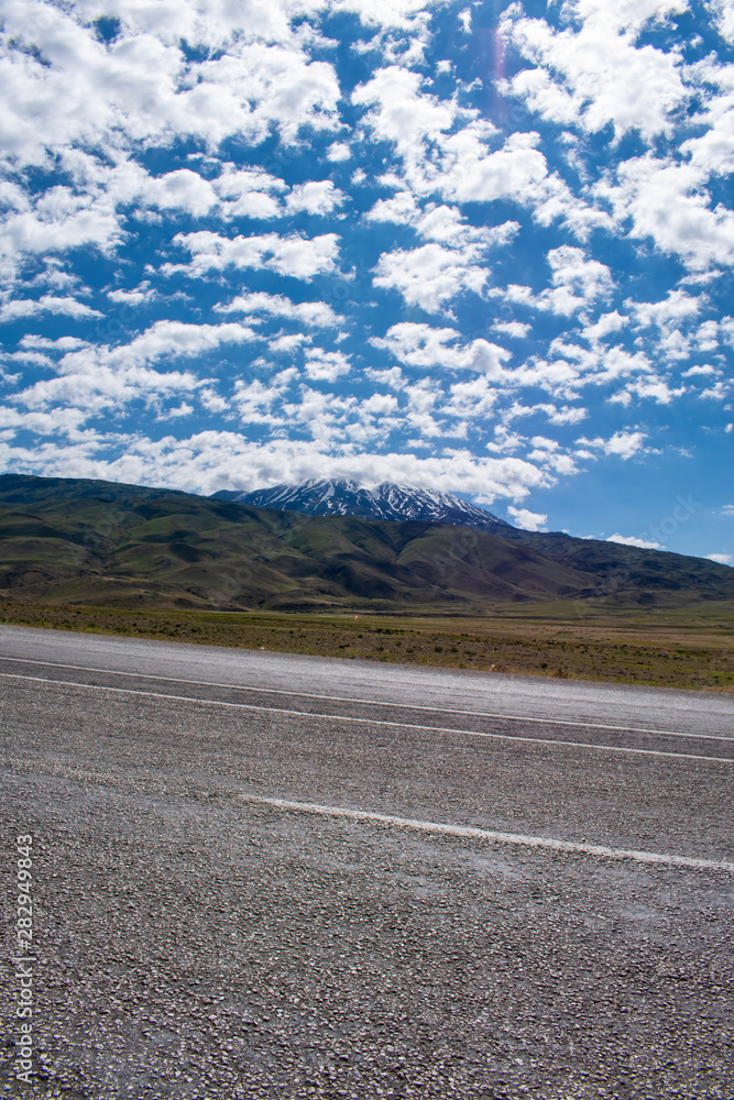 Fototapeta premium Road from Igdir to Dogubayazıt: Mount Ararat, Agri Dagi, the highest mountain in the extreme east of Turkey, the resting place of Noah's Ark for Christianity, snow-capped and dormant compound volcano