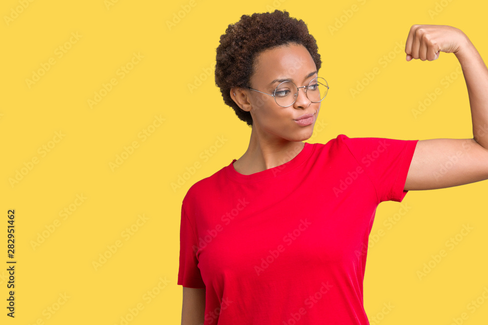 Beautiful young african american woman wearing glasses over isolated background Strong person showing arm muscle, confident and proud of power Beautiful young african american woman wearing glasses over isolated background Strong person showing arm muscle, confident and proud of power
