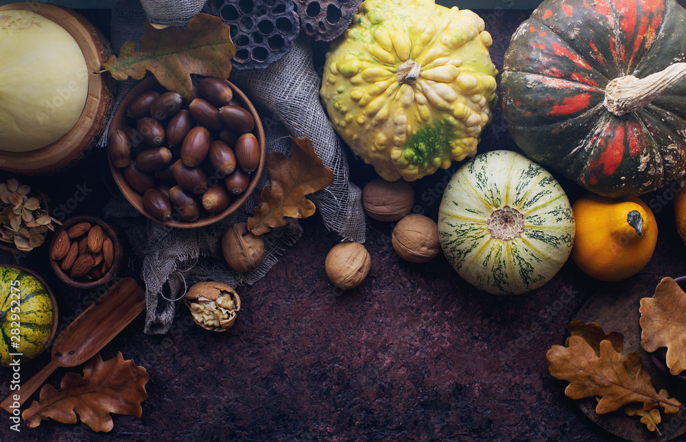 Autumn background with decorative pumpkin, corn, wallnuts, autumn leaves, acorns on dark stone table Autumn background with decorative pumpkin, corn, wallnuts, autumn leaves, acorns on dark stone table