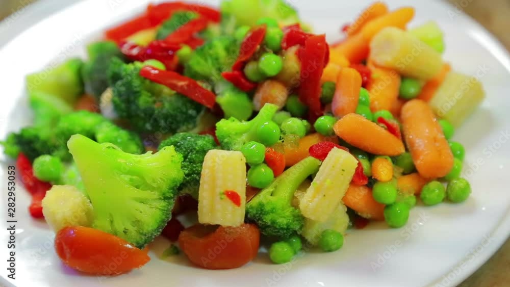 Broccoli, corn, pepper on a white plate rotate in a circle Broccoli, corn, pepper on a white plate rotate in a circle