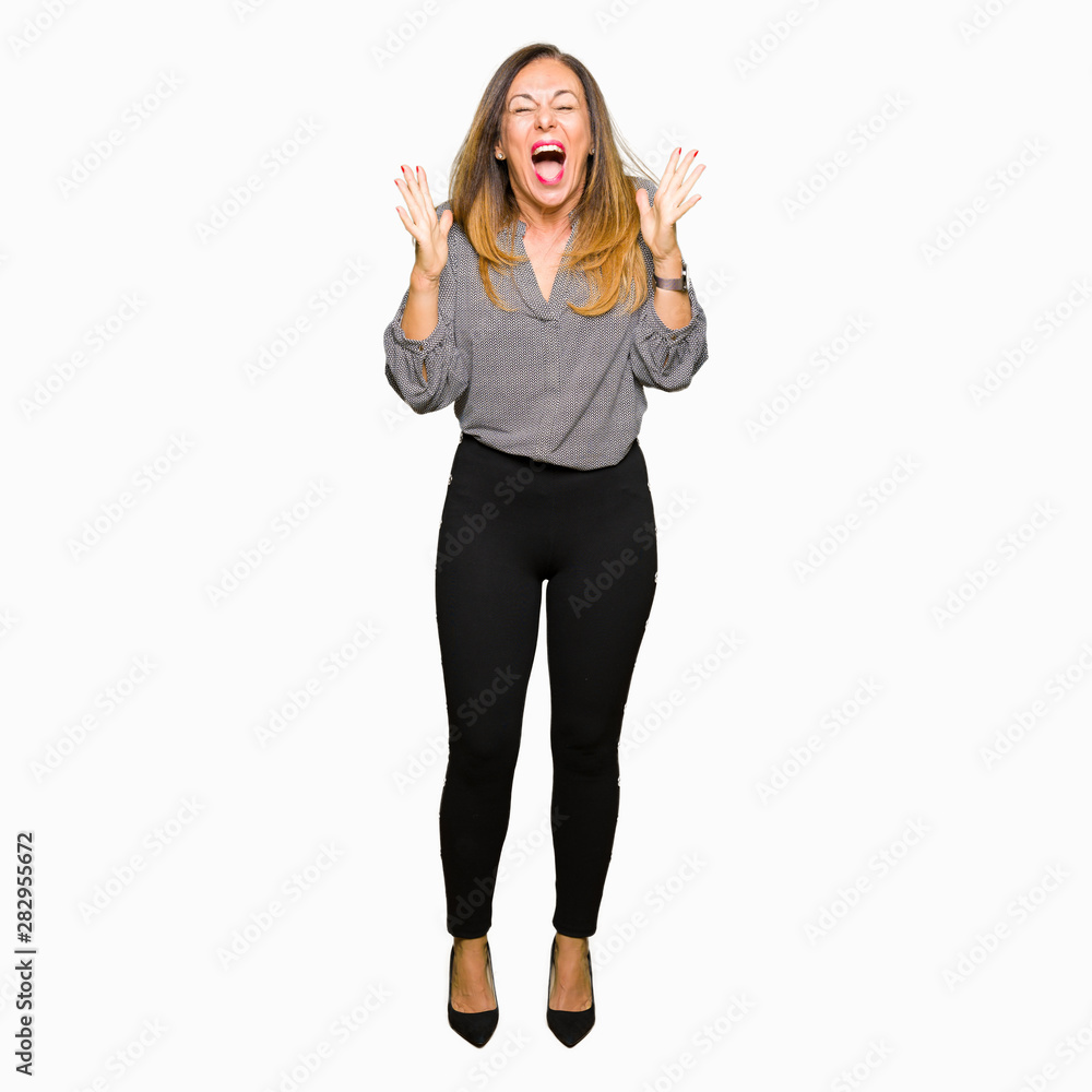 Beautiful middle age business woman celebrating mad and crazy for success with arms raised and closed eyes screaming excited. Winner concept Beautiful middle age business woman celebrating mad and crazy for success with arms raised and closed eyes screaming excited. Winner concept