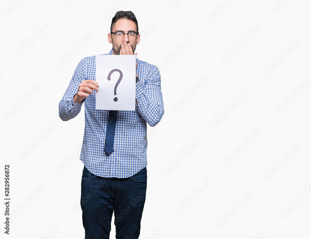 Handsome young business man holding paper with question mark over isolated background cover mouth with hand shocked with shame for mistake, expression of fear, scared in silence, secret concept