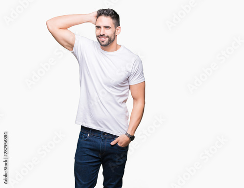 Handsome man wearing white t-shirt over white isolated background Smiling confident touching hair with hand up gesture, posing attractive