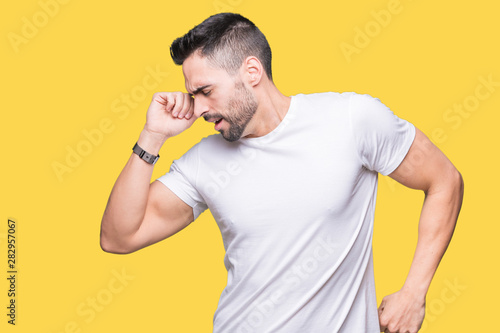 Handsome man wearing white t-shirt over yellow isolated background stretching back, tired and relaxed, sleepy and yawning for early morning