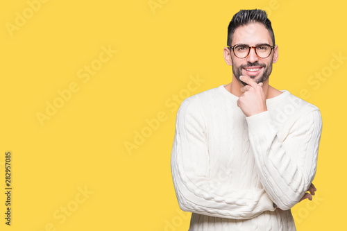 Young handsome man wearing glasses over isolated background looking confident at the camera with smile with crossed arms and hand raised on chin. Thinking positive.