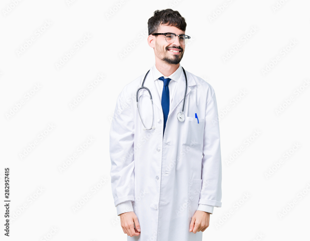 Young doctor man wearing hospital coat over isolated background looking away to side with smile on face, natural expression. Laughing confident.