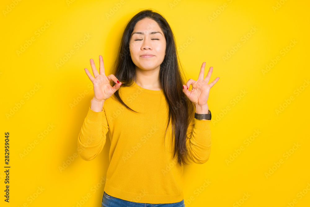 Beautiful brunette woman over yellow isolated background relax and smiling with eyes closed doing meditation gesture with fingers. Yoga concept. Beautiful brunette woman over yellow isolated background relax and smiling with eyes closed doing meditation gesture with fingers. Yoga concept.