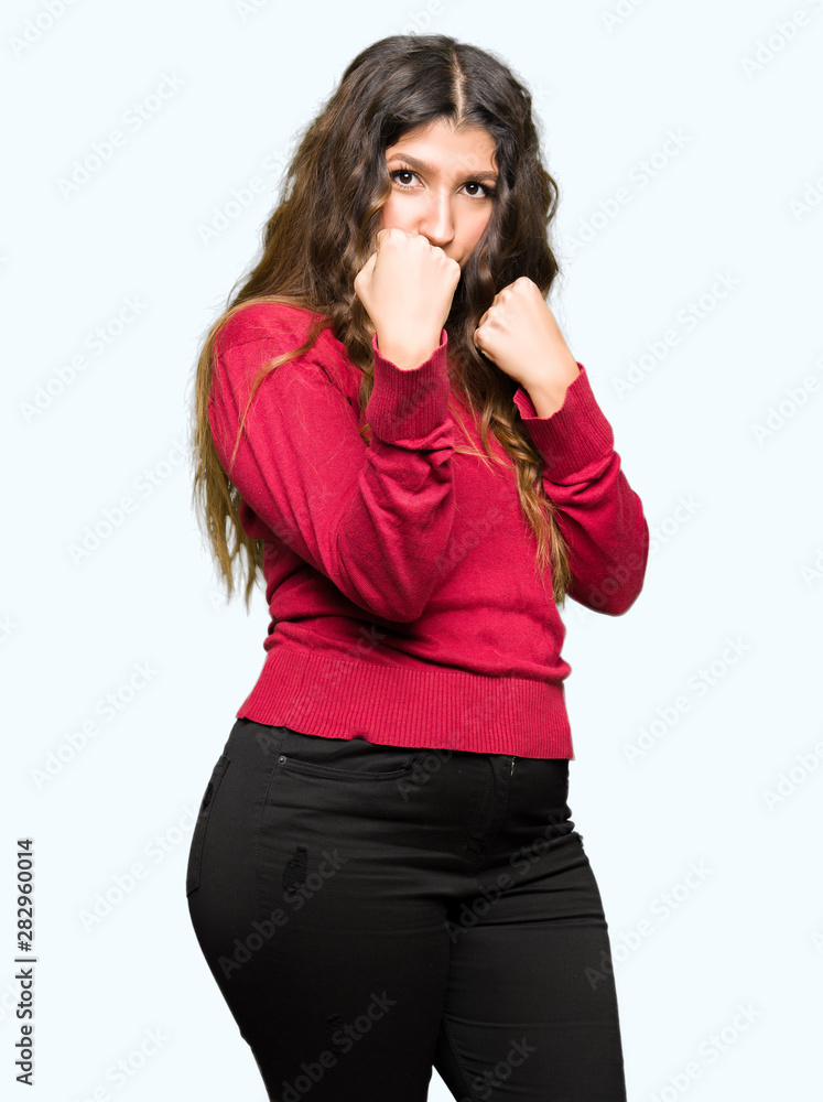 Young beautiful woman wearing red sweater Ready to fight with fist defense gesture, angry and upset face, afraid of problem Young beautiful woman wearing red sweater Ready to fight with fist defense gesture, angry and upset face, afraid of problem