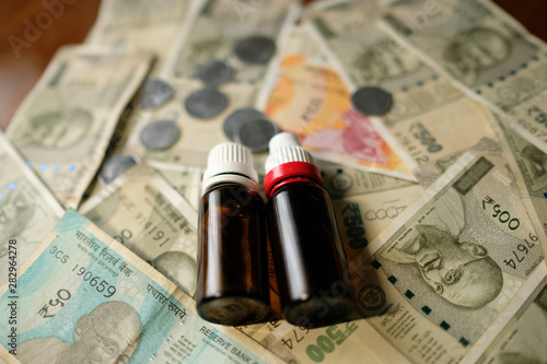 two Empty Medicine bottles on Indian currency notes. Isolated focus. Medicine bill concept 