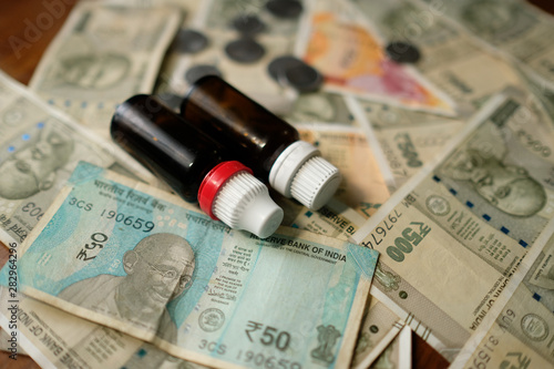 two Empty Medicine bottles on Indian currency notes. Isolated focus. Medicine bill concept 
