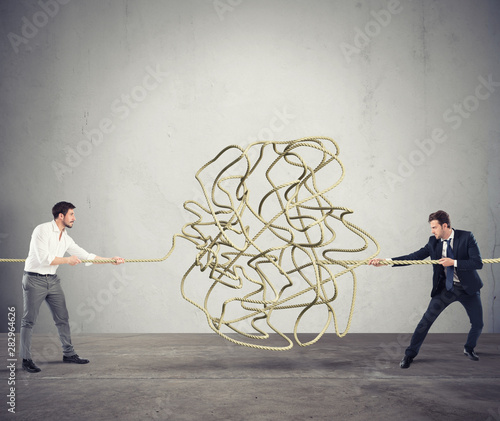 Businessmen try to solve a tangled rope. Concept of partnership photo