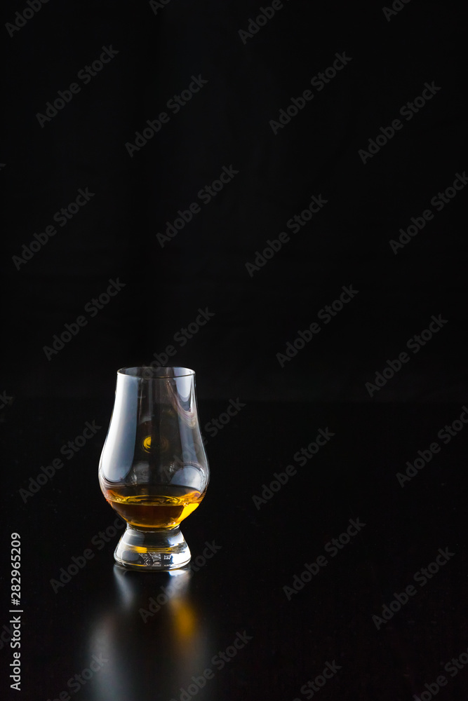 A pour of whiskey in a glencairn glass. A pour of whiskey in a glencairn glass.