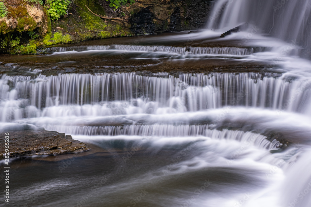 Obraz premium waterfall at belfountain conservation area Ontario Canada with trees, rocks, bridge, and long exposure