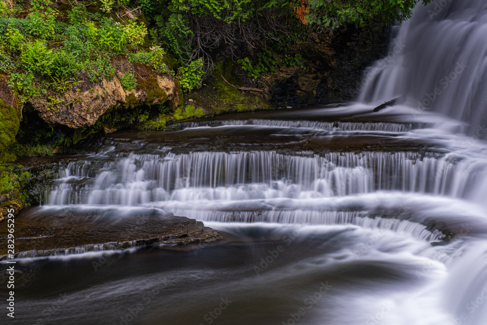 Fototapeta premium waterfall at belfountain conservation area Ontario Canada with trees, rocks, bridge, and long exposure